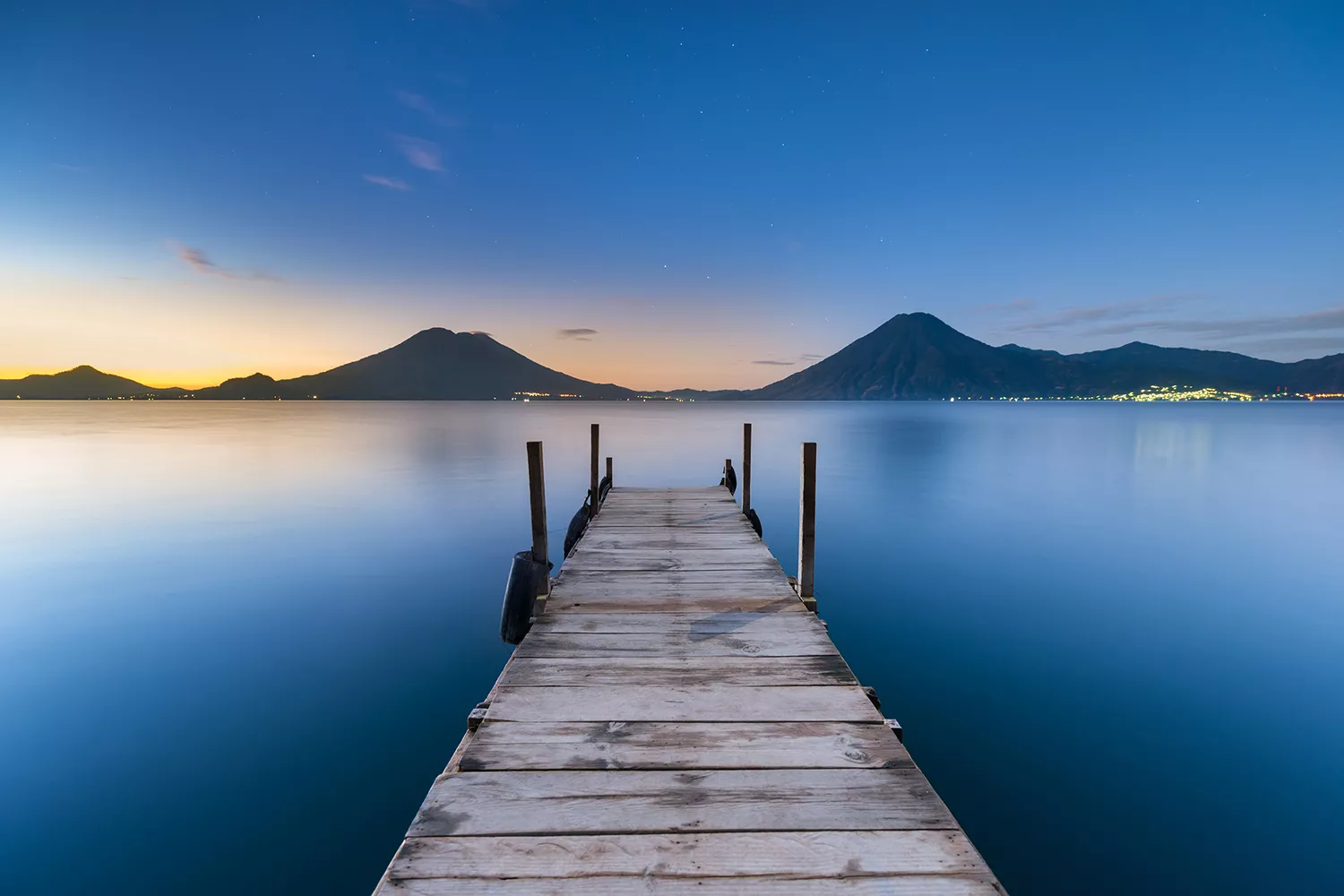 A view looking down a wharf on Lake Atitlán at sunrise.